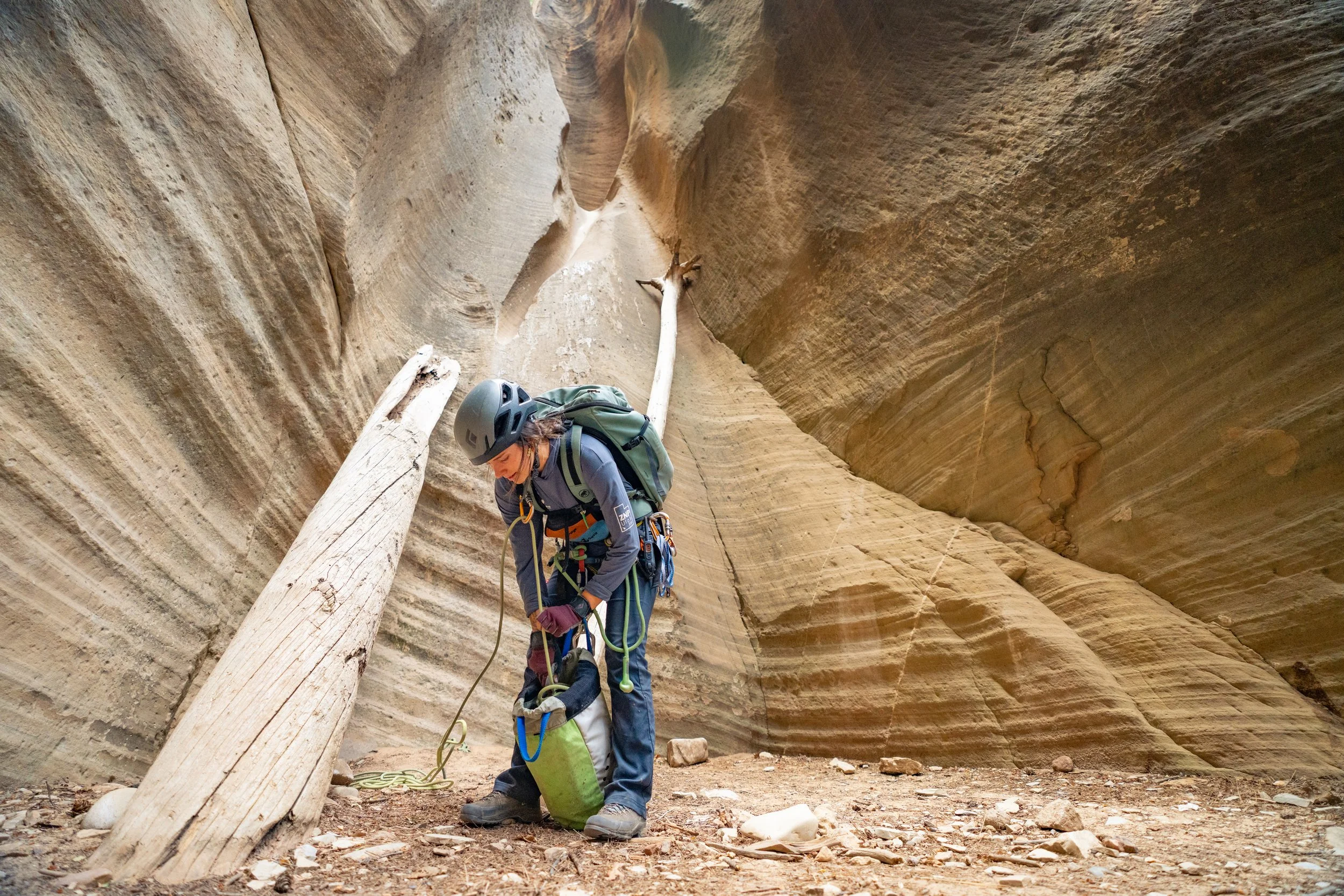 A close-up photo of canyoneering boots, neoprene socks, and a wooden hiking stick laid out on a bench outside an outfitter in Springdale, Utah, in natural daylight