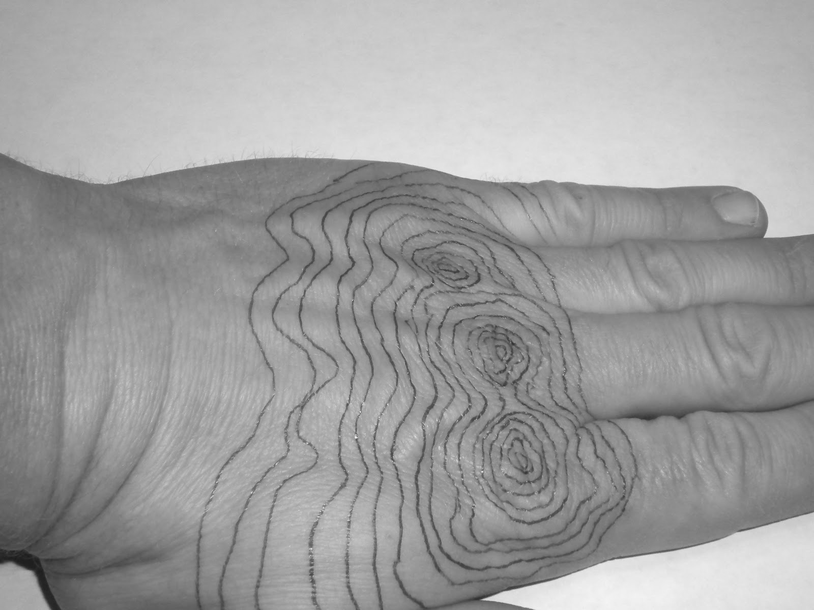 A close-up photograph of a topographic map held in two hands, showing dense contour lines, a marked trail, and elevation numbers on index contours, realistic outdoor lighting