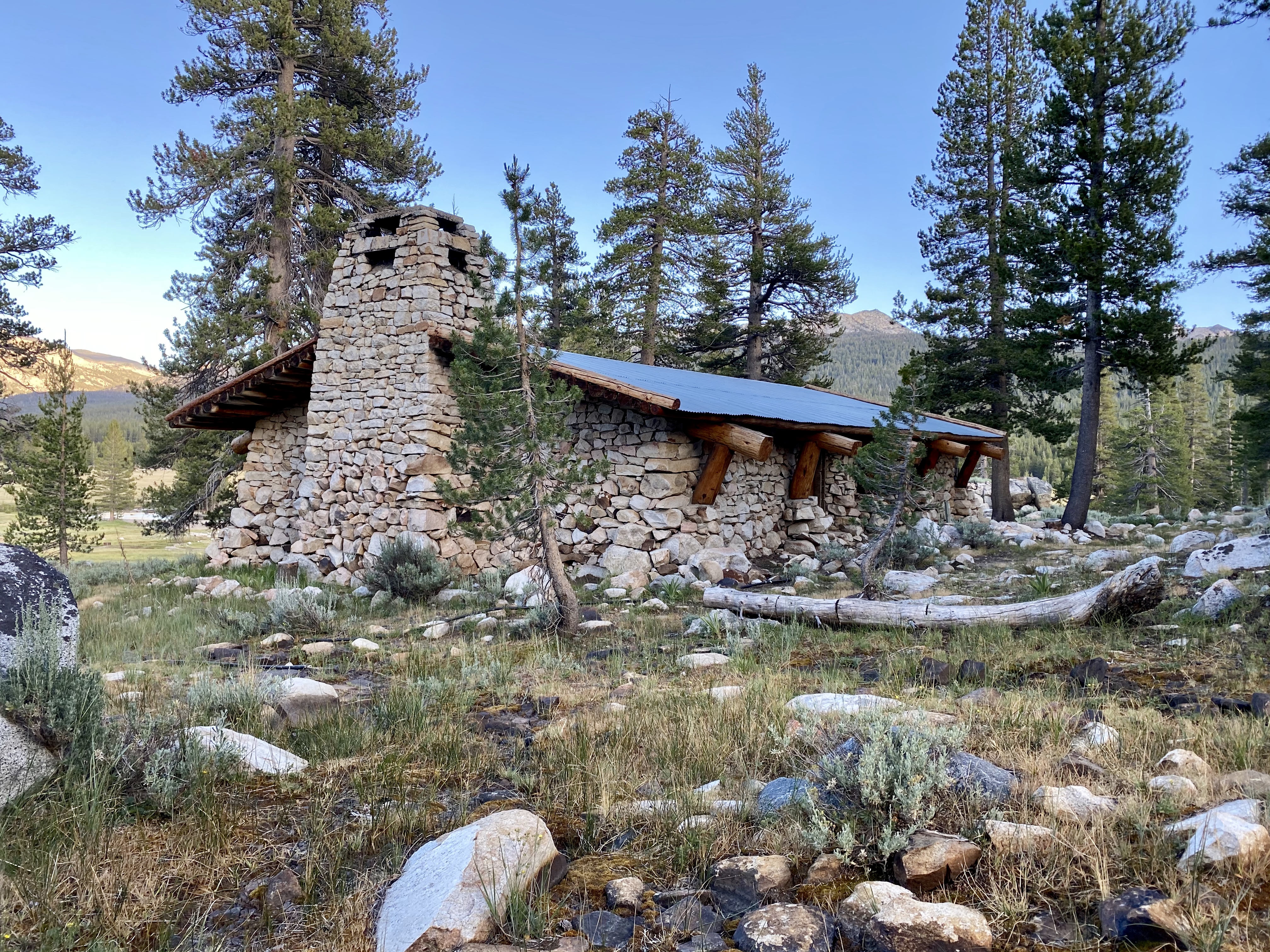 A crisp photograph of Parsons Memorial Lodge, a small stone building near Tuolumne Meadows, with surrounding pines and bright summer light