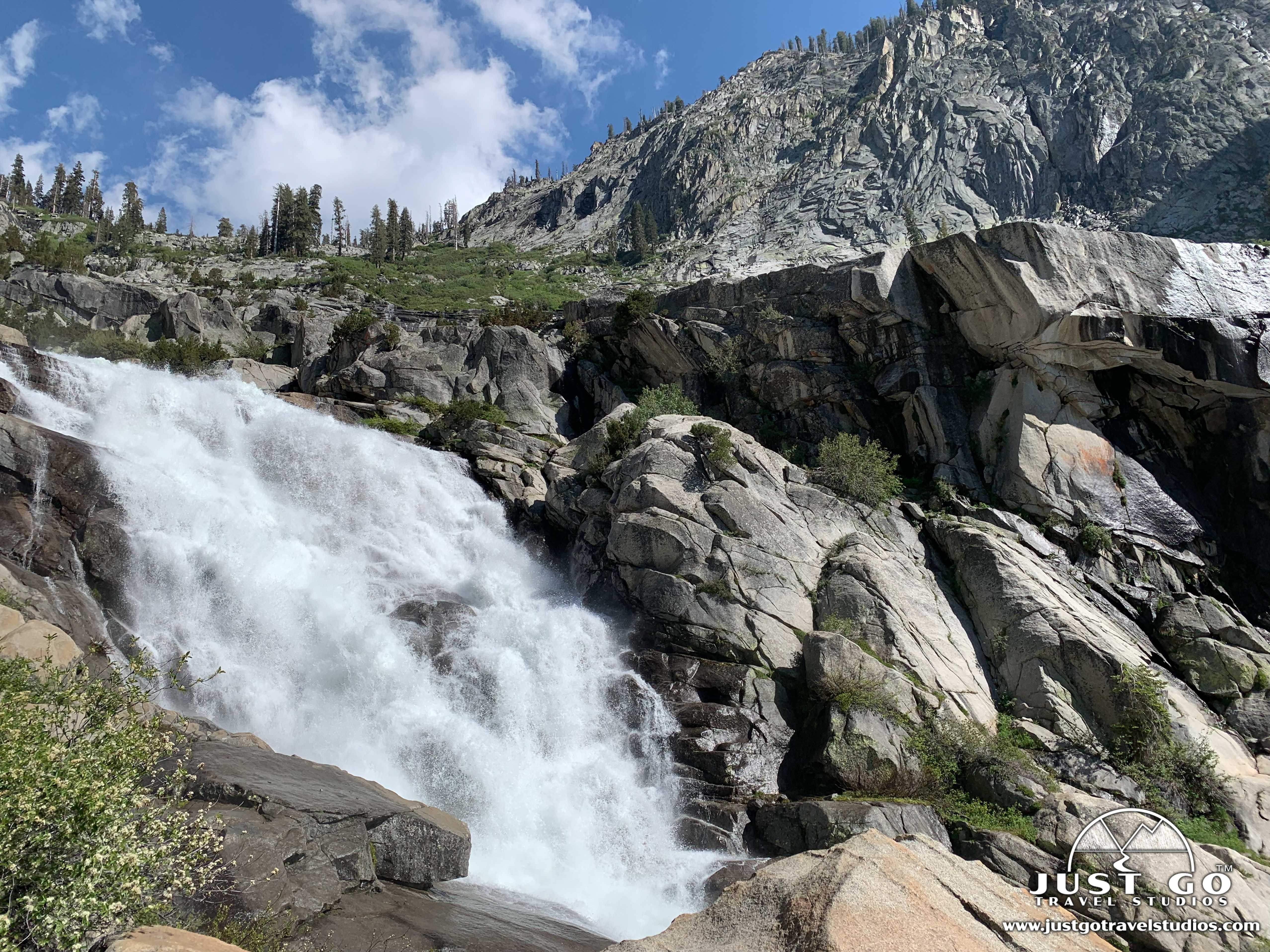 A dirt trail beside the Marble Fork Kaweah River on the Tokopah Falls hike in Sequoia National Park with granite walls rising in the background, realistic outdoor photograph