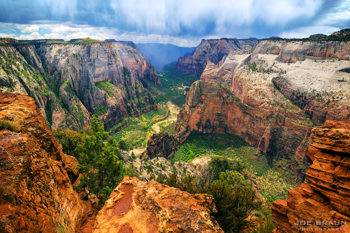 A hiker standing near the edge at Observation Point in Zion National Park looking down into Zion Canyon with Angels Landing visible far below