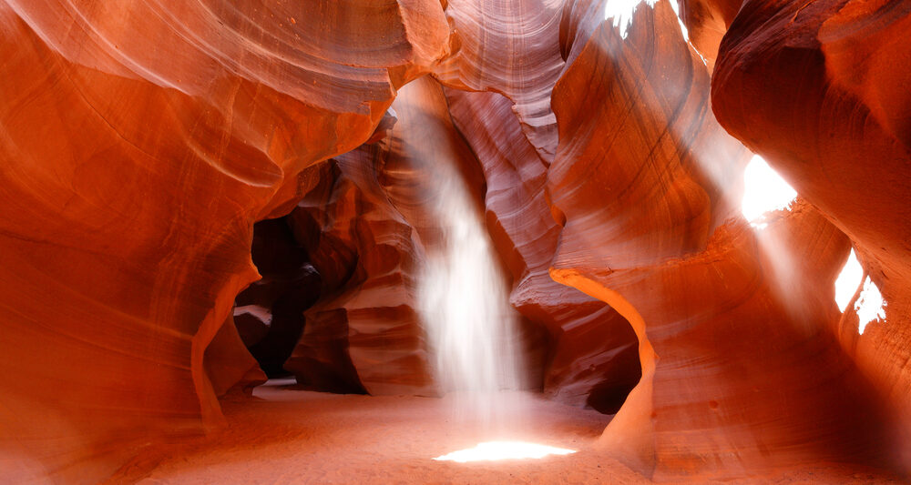 A narrow sandstone slot canyon with a visible line of sticks and leaves caught high on the wall, indicating a recent flood level, realistic outdoor photography