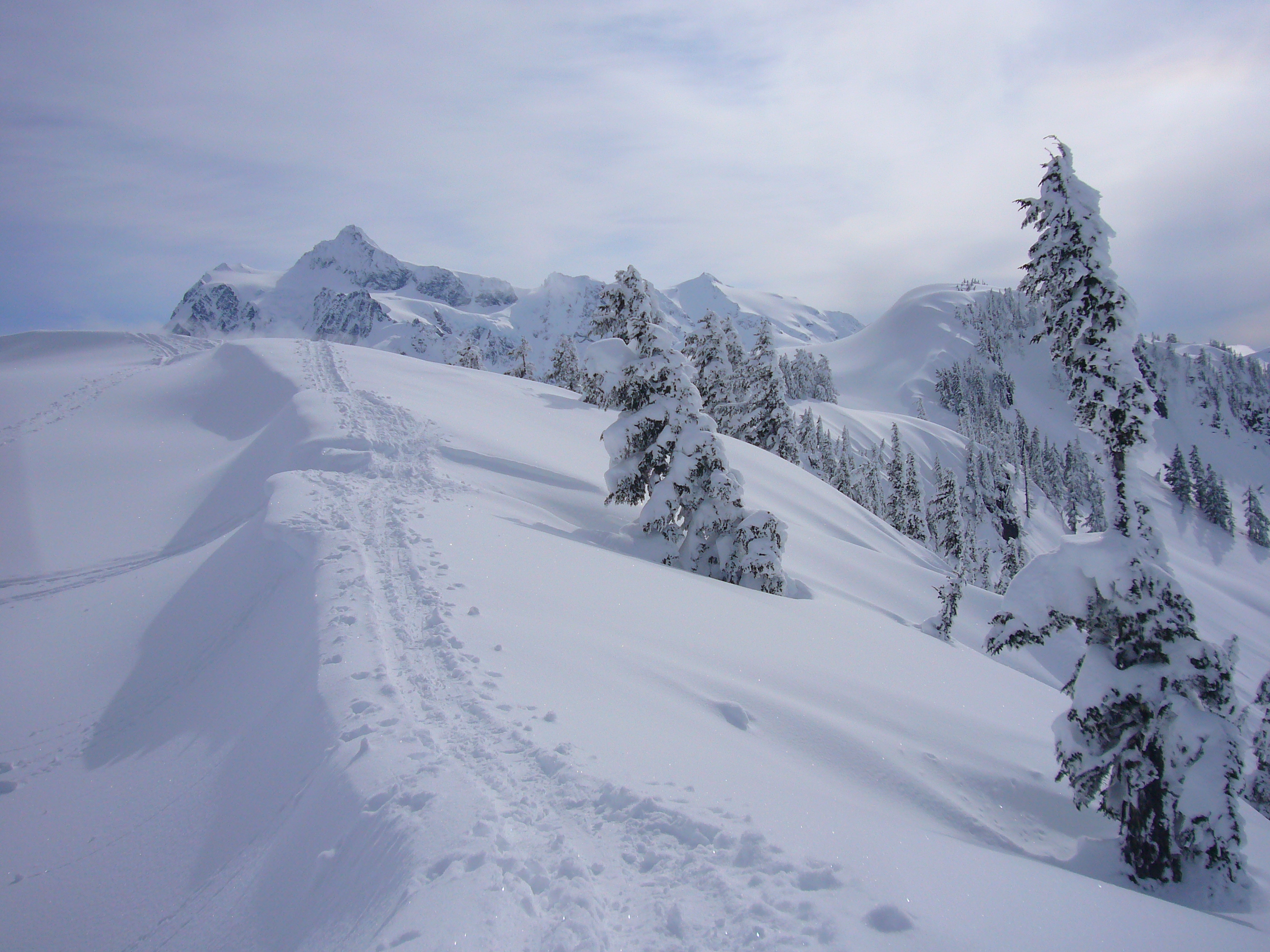 A photograph from Artist Point on the Mount Baker Highway with snowbanks framing the road and Mount Shuksan glowing in late afternoon light
