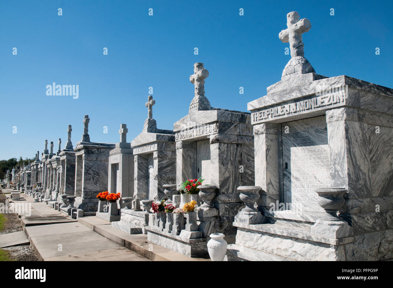 A quiet above-ground cemetery in New Orleans with weathered marble tombs and soft afternoon light, real travel photography style