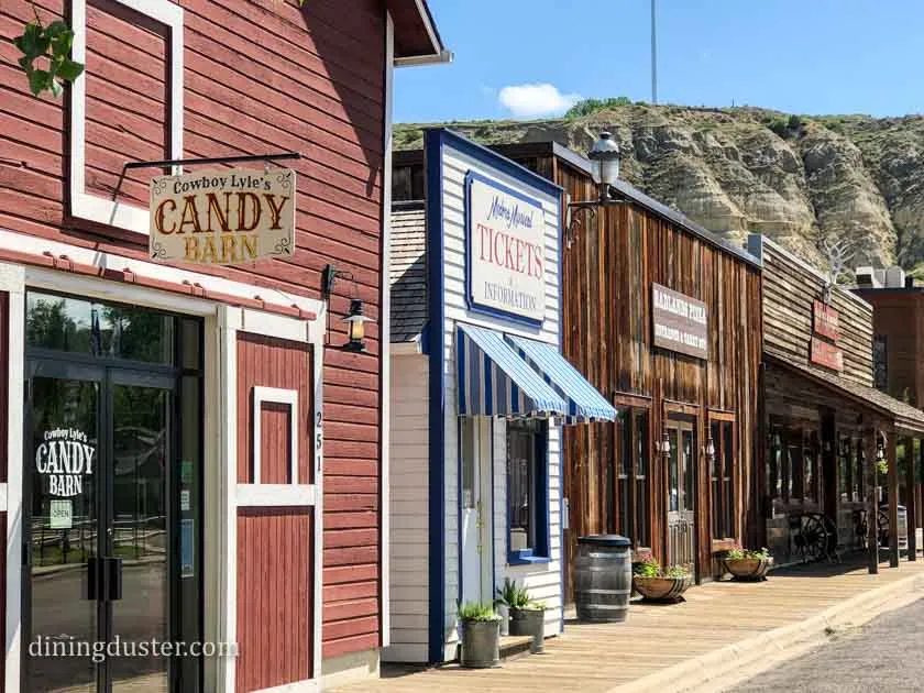 A quiet main street in Medora, North Dakota with historic storefronts and parked cars in warm evening light, travel photography