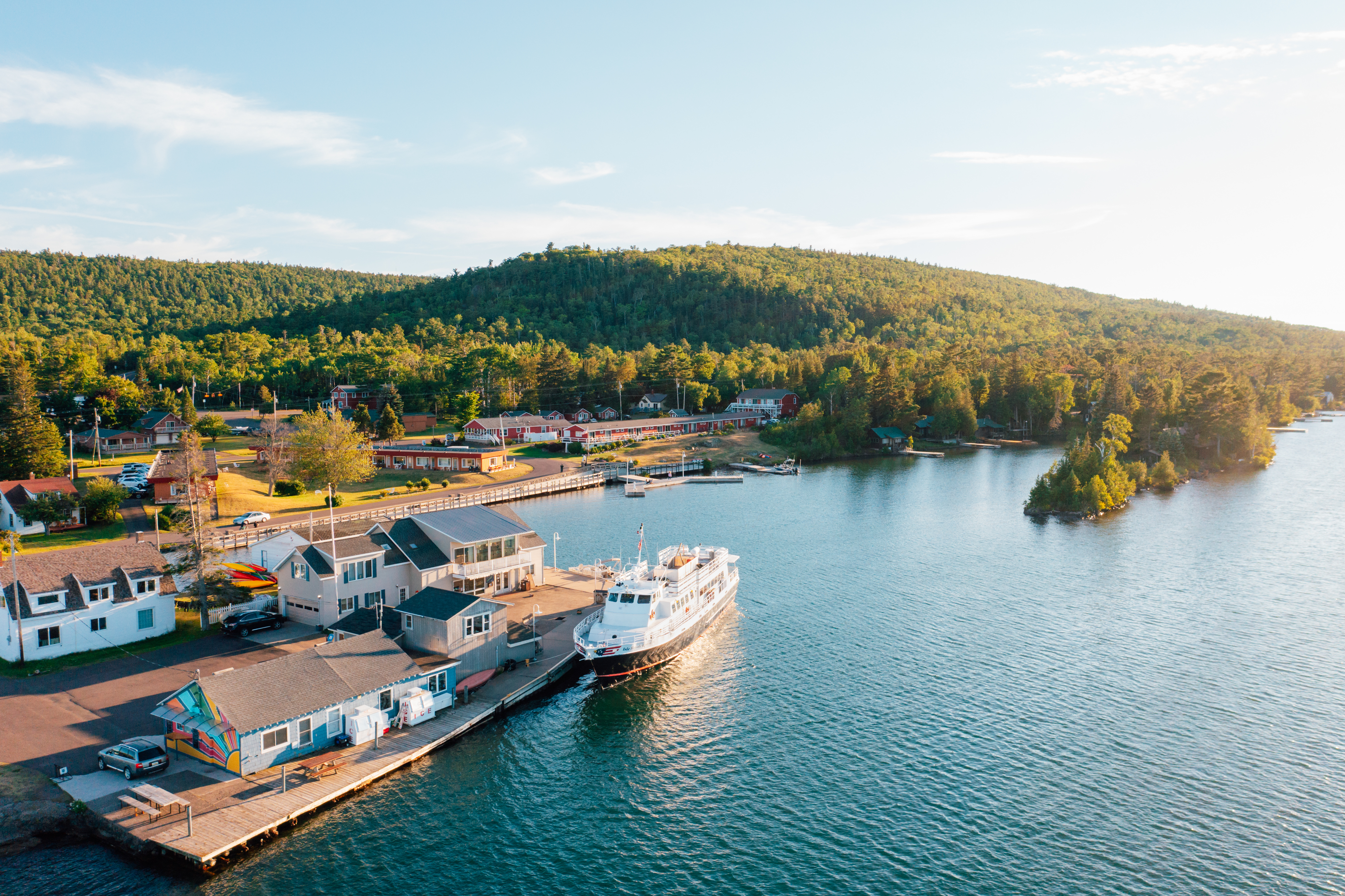 A real-life photograph of a passenger ferry tied up at the dock in Copper Harbor, Michigan with Lake Superior stretching behind it on a clear morning