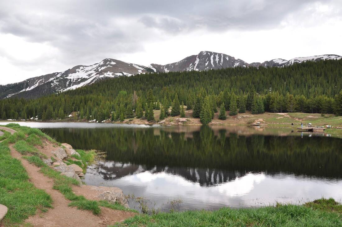 A real photograph of Andrews Lake near Molas Pass with a forested shoreline and rugged mountains rising behind under bright summer sky