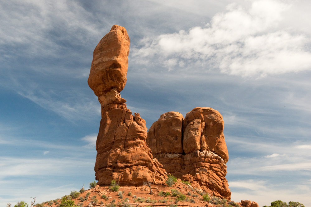 A real photograph of Balanced Rock in Arches National Park standing tall above the desert floor in bright midday light