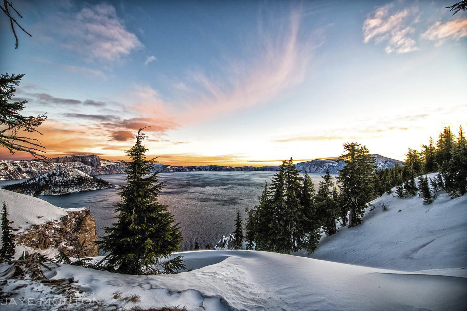 A real photograph of Crater Lake at sunset from the rim, with warm light on the caldera walls and the lake turning a darker blue