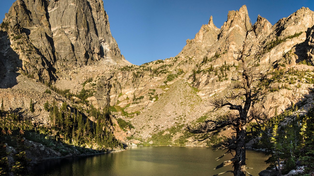 A real photograph of Emerald Lake in Rocky Mountain National Park with turquoise water, steep granite walls, and patches of snow along the shoreline
