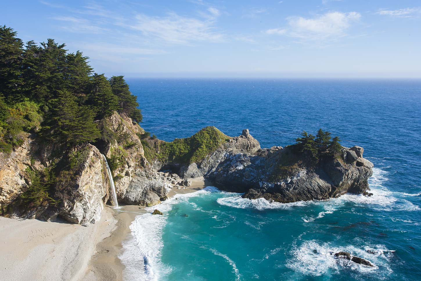 A real photograph of McWay Falls in Julia Pfeiffer Burns State Park cascading from a coastal cliff into a small sandy cove with turquoise water