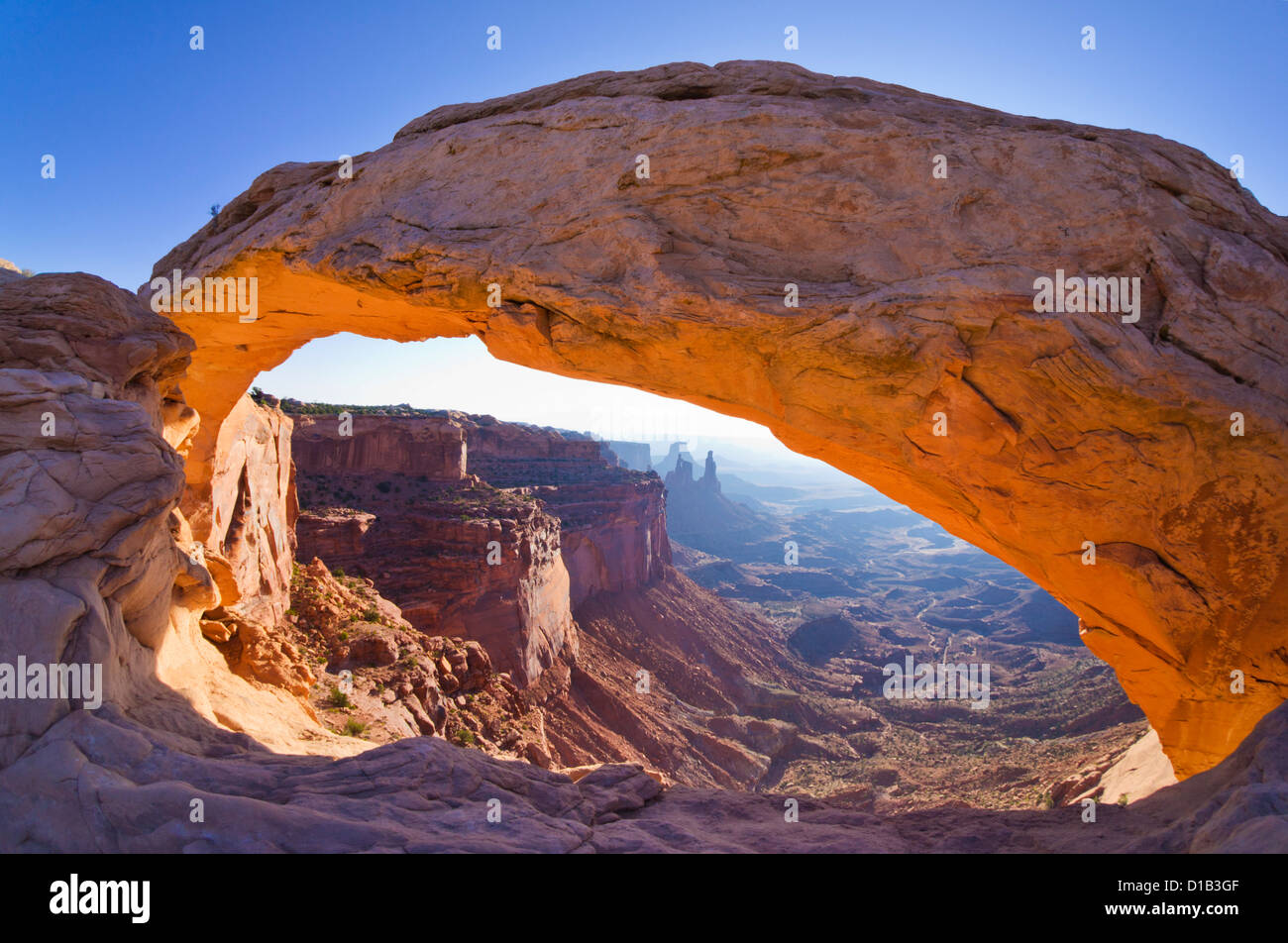 A real photograph of Mesa Arch in Canyonlands Island in the Sky with early morning light glowing under the arch and a canyon vista beyond