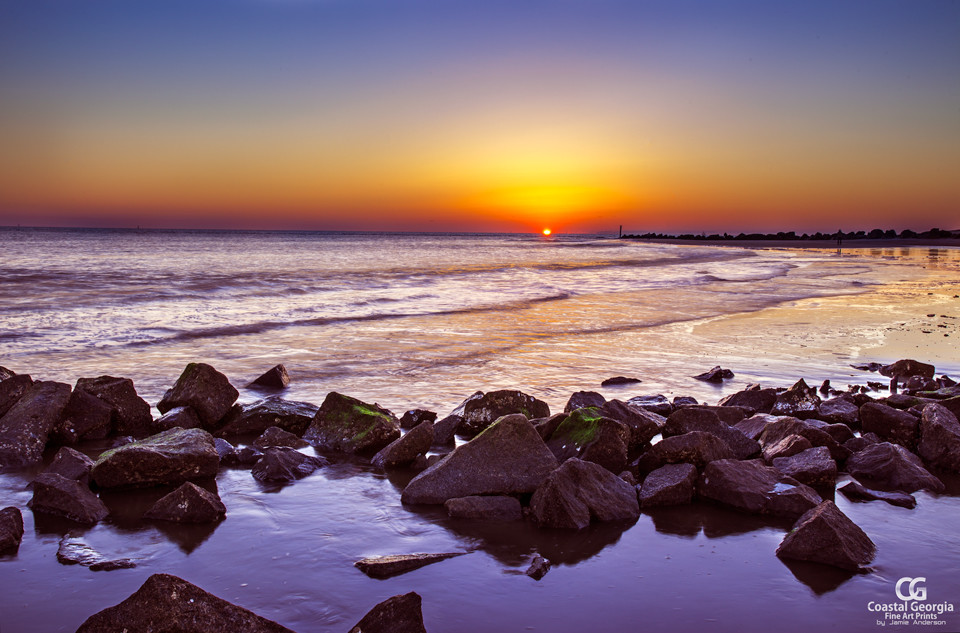 A real photograph of Tybee Island beach with gentle waves rolling in and a soft sunrise glow over the Atlantic Ocean