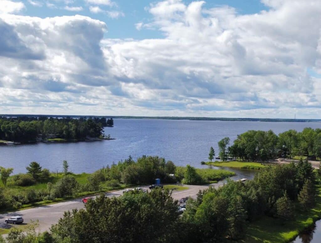 A real photograph of a public boat launch on Rainy Lake in Voyageurs National Park with a pickup truck backing a small boat trailer down the ramp