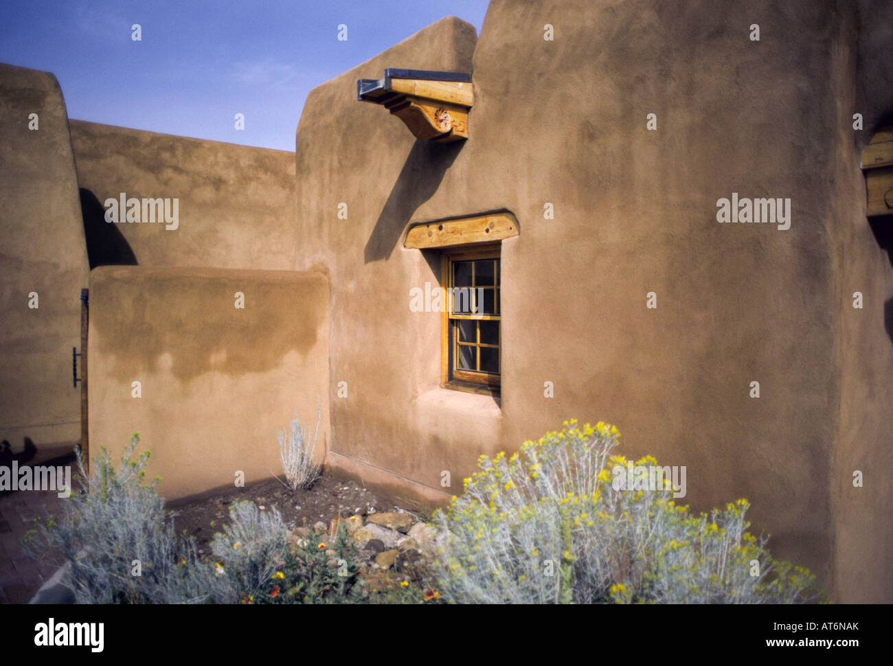 A real photograph of adobe buildings near the Santa Fe Plaza in warm morning light with pedestrians walking past brick paths and shaded portals
