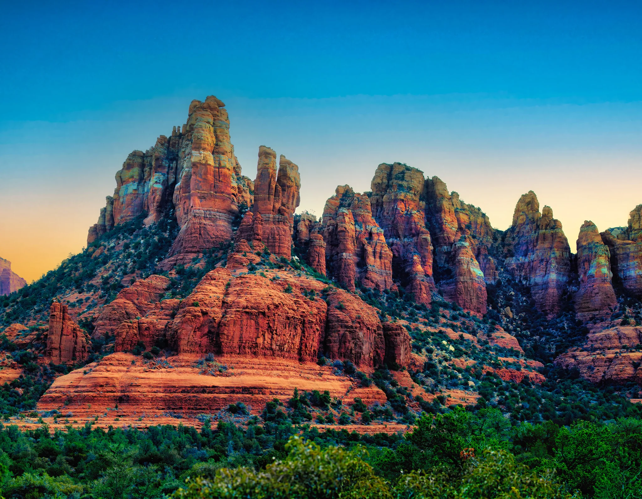 A real photograph of red rock formations in Sedona, Arizona at sunrise, with warm light hitting the cliffs and a clear desert sky