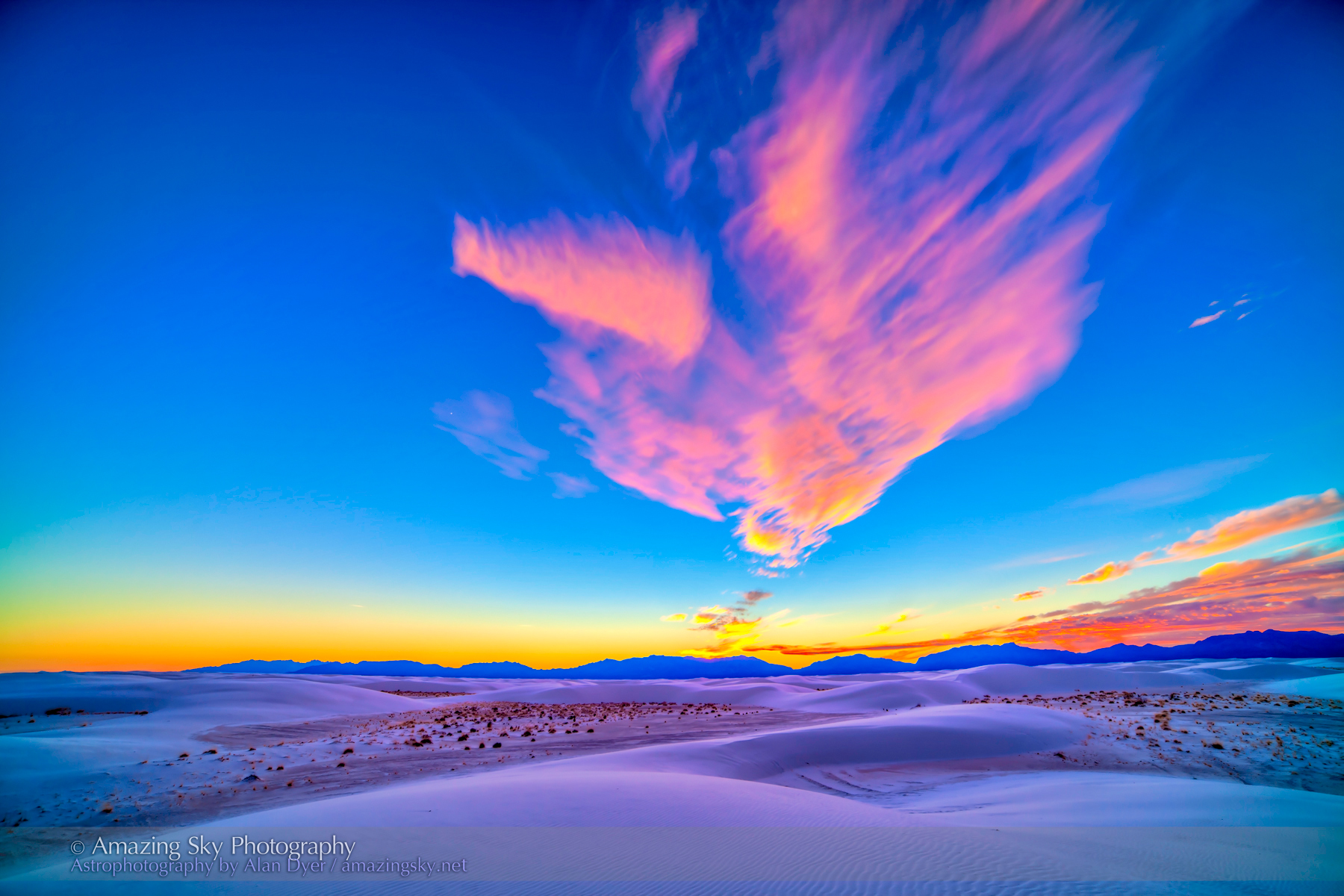 A real photograph of rippled white gypsum sand dunes glowing at sunset in White Sands National Park, with long shadows and a clear sky
