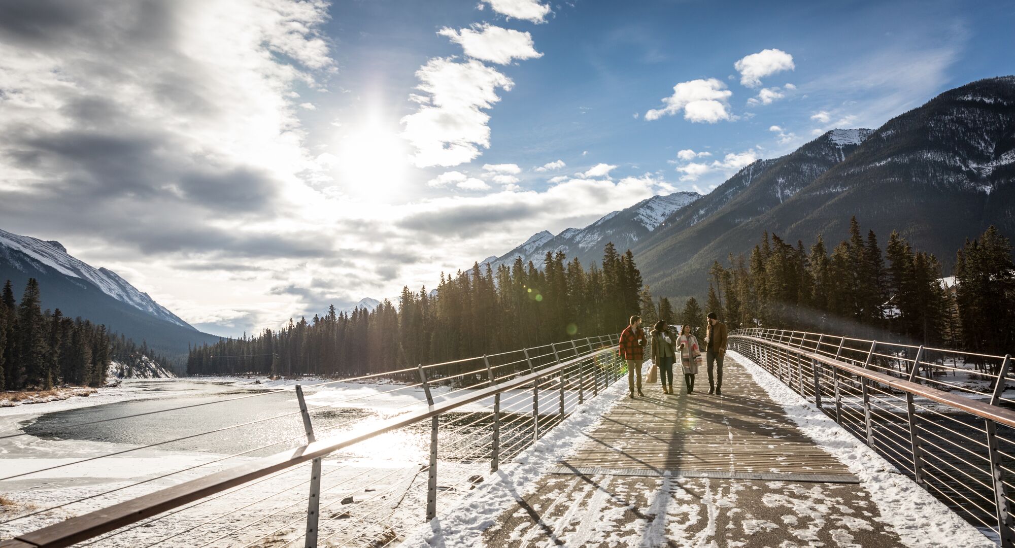 A real photograph of the Bow River pathway near Banff town in the morning, with evergreen trees, a gravel path, and mountains in the distance