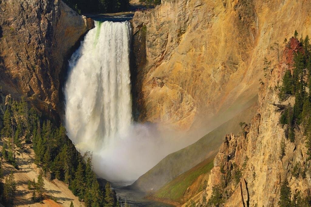 A real photograph taken from Artist Point showing the Lower Falls of the Yellowstone River plunging into the Grand Canyon of the Yellowstone with colorful canyon walls and rising mist