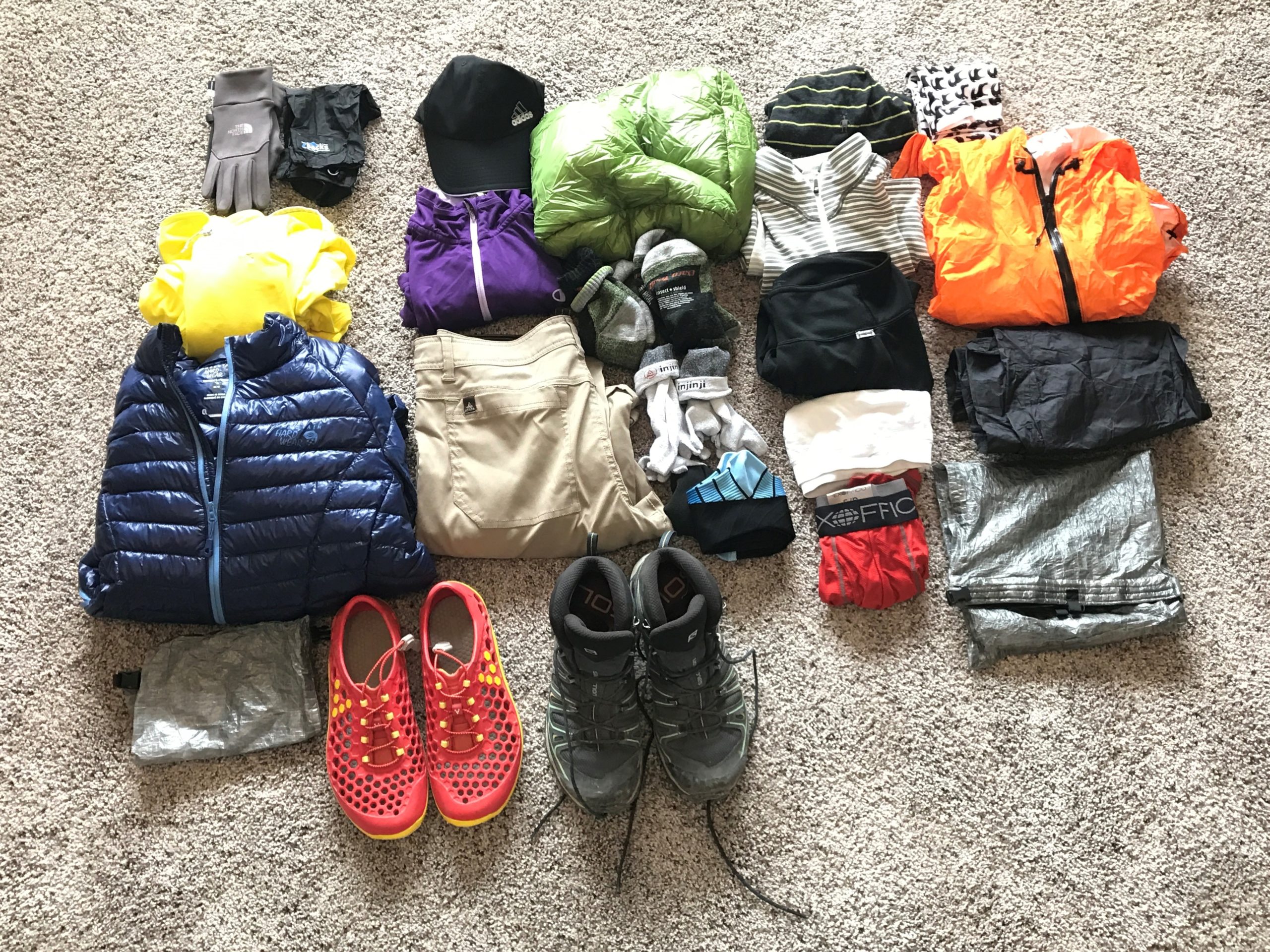 A realistic photograph of hiking pants and socks hanging outdoors to dry after being treated with permethrin, soft natural light