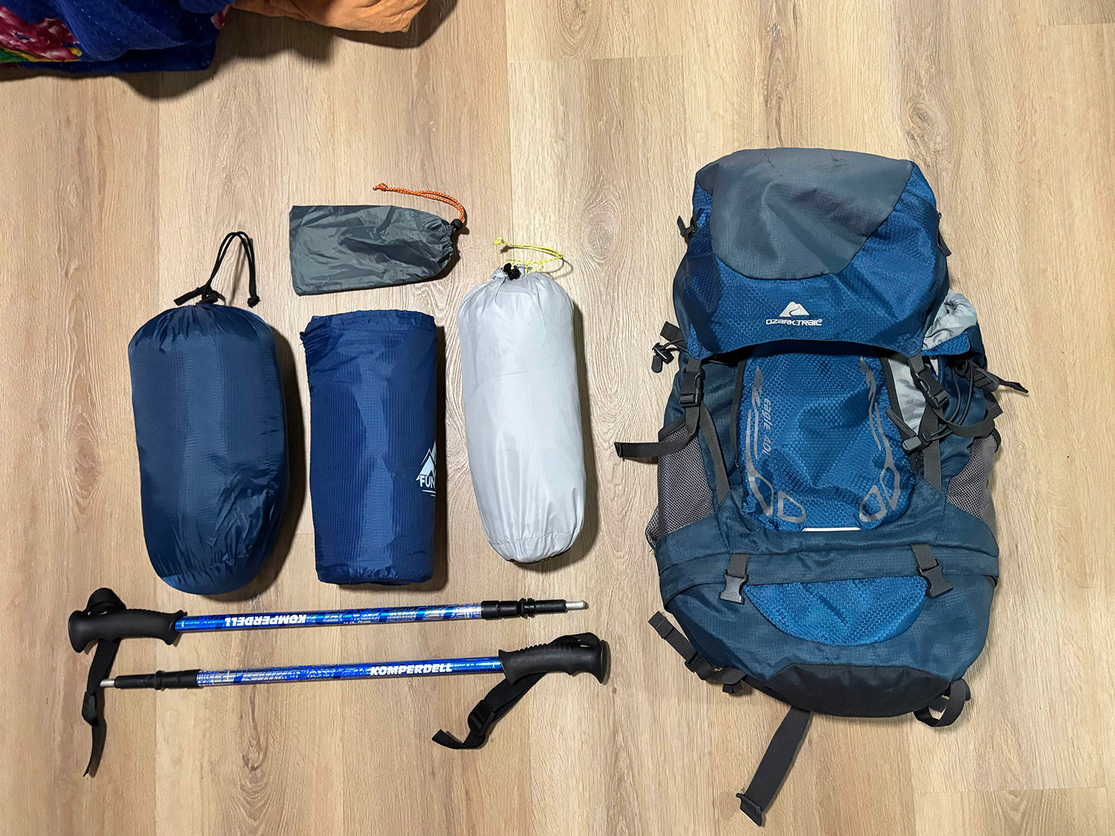 A small daypack on a bench with sunscreen, sunglasses, a reusable water bottle, and a compact towel laid out for a Catalina Island day trip, realistic travel photo