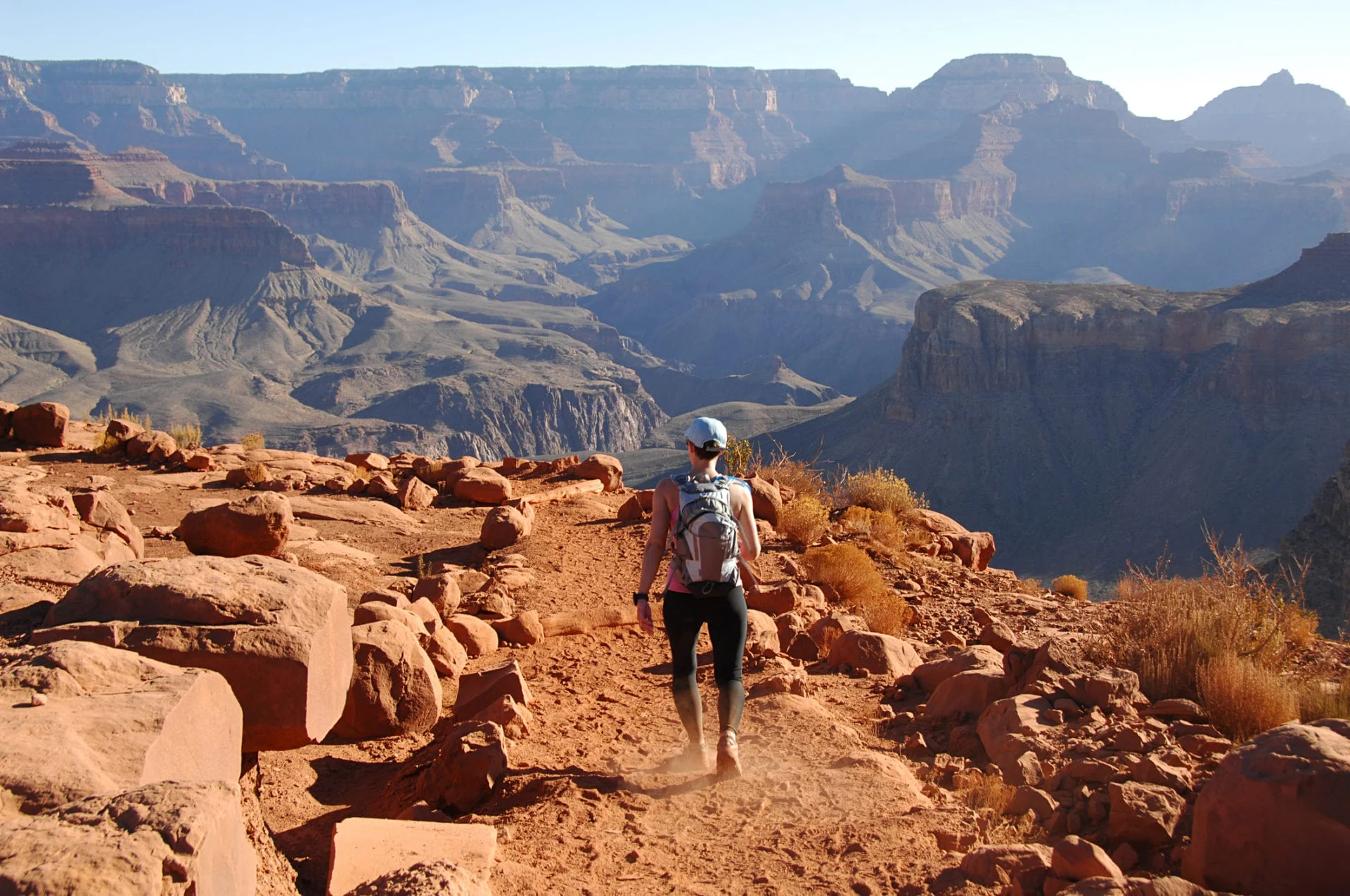 A small group of hikers at a Grand Canyon trailhead before sunrise wearing headlamps and packs, real photo with cool blue pre-dawn light