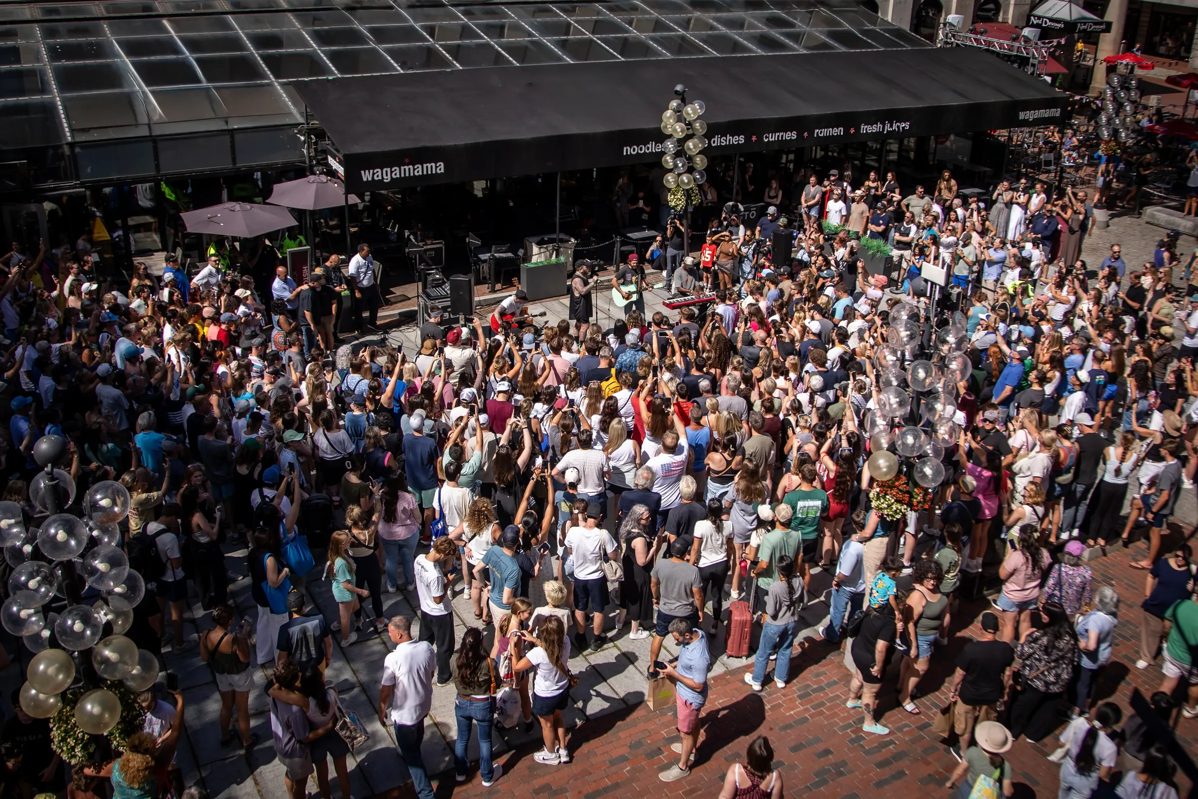 A street photograph of Faneuil Hall Marketplace in Boston with pedestrians, food stalls, and historic brick architecture