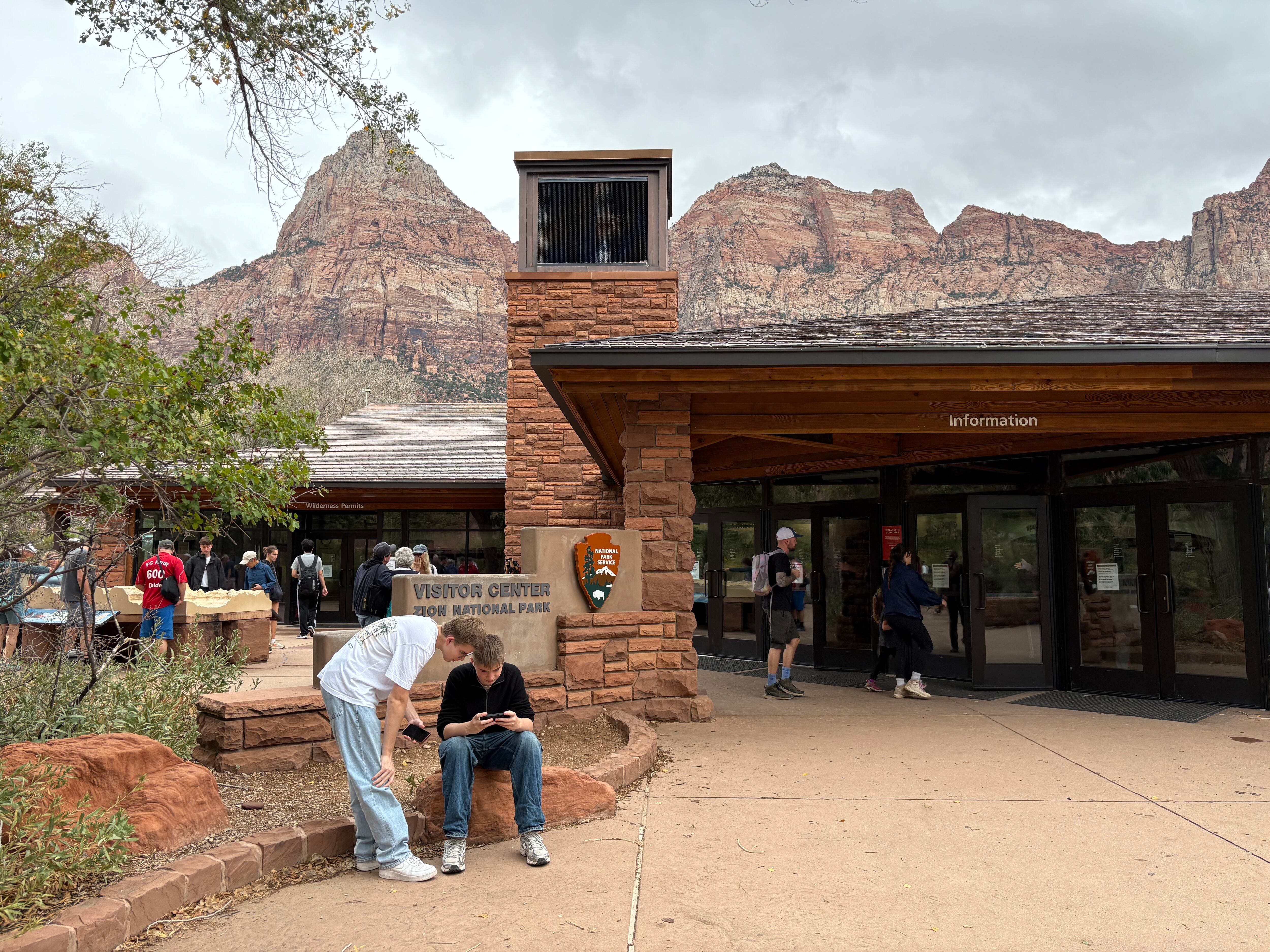 A traveler holding paperwork at a national park wilderness permit counter inside a visitor center, documentary travel photo