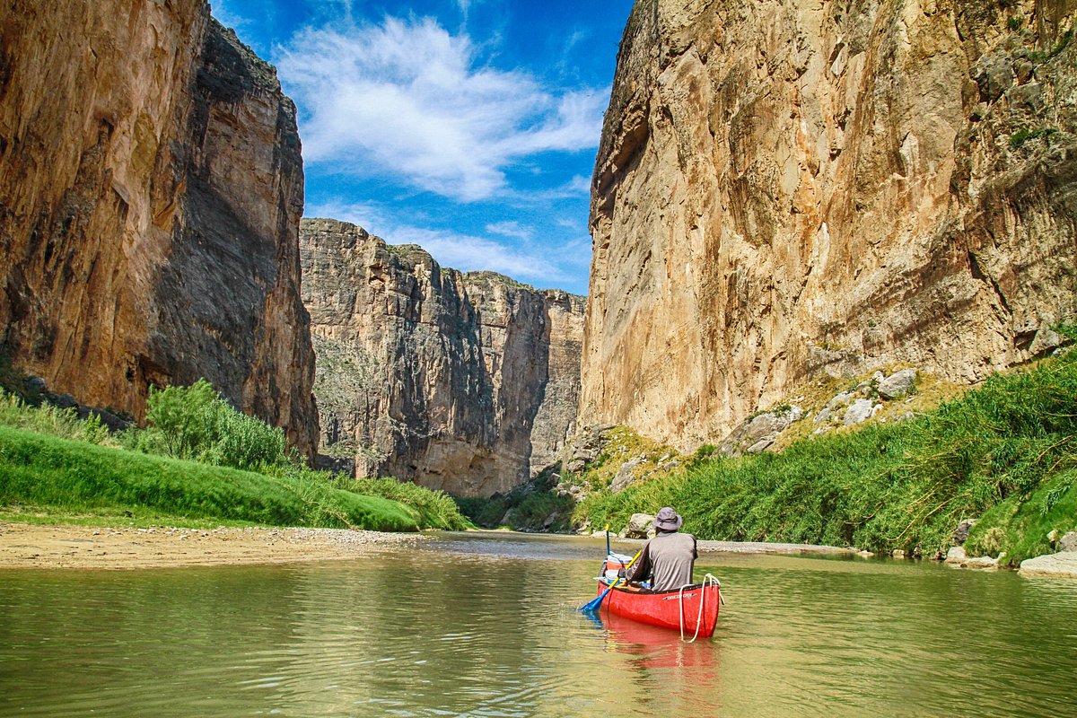 A wide view into Santa Elena Canyon in Big Bend National Park with towering limestone walls and the Rio Grande flowing through the canyon, late afternoon desert light