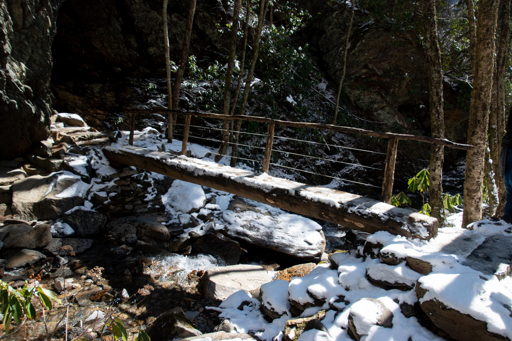 An icy wooden log bridge on the Alum Cave Trail with hikers stepping carefully