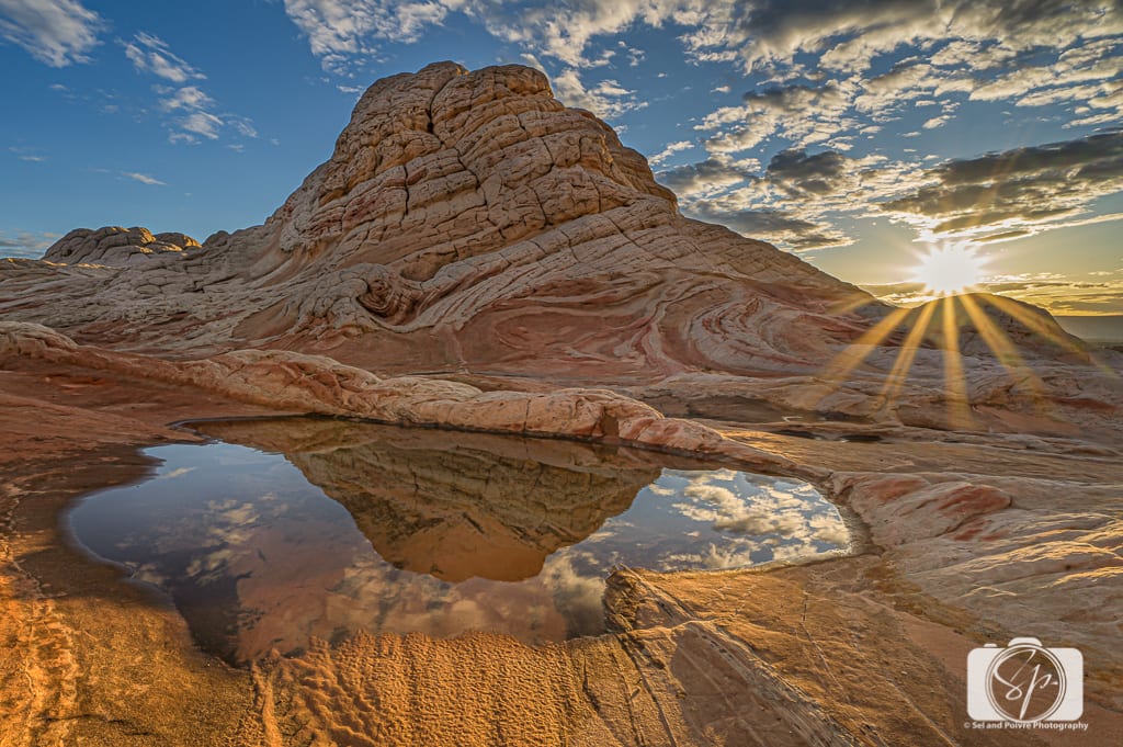 Early morning sunlight hitting the swirling white and tan sandstone formations at White Pocket, Arizona, with long shadows and a wide desert sky