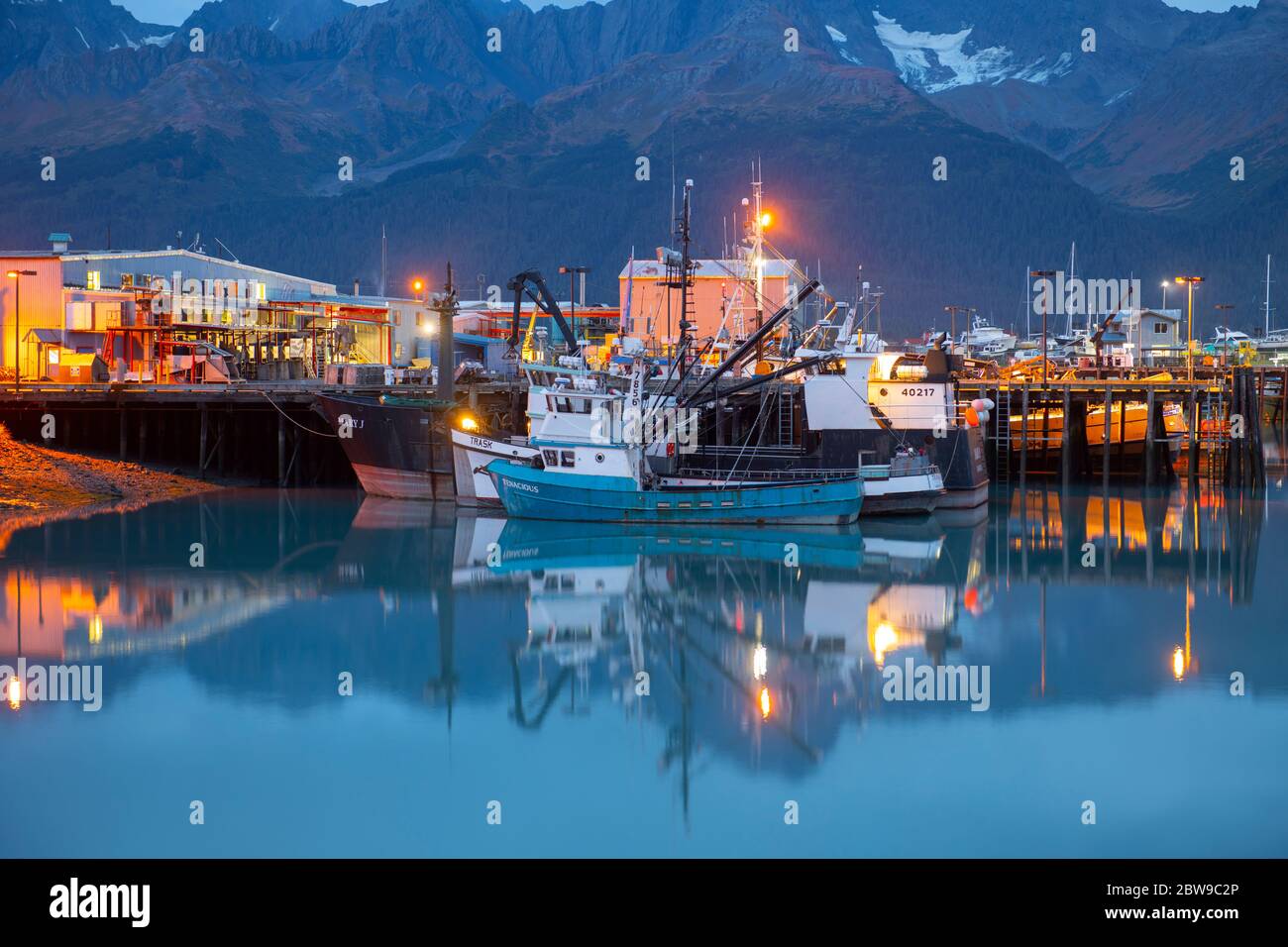 Fishing boats moored in the Seward small boat harbor during a calm summer evening with soft light on the surrounding mountains, real travel photograph