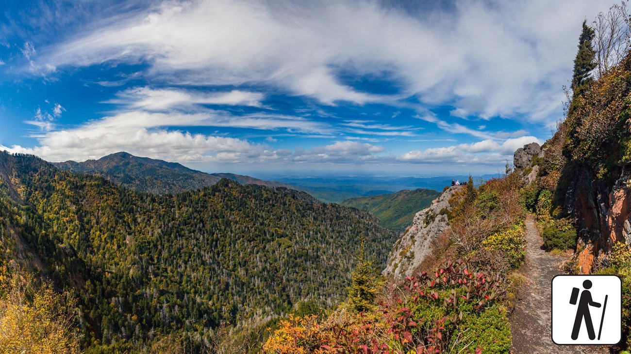 Hiker standing near the rocky outcrop at Charlies Bunion with sweeping views of the Smoky Mountains, clear sky and rugged cliff edge, real outdoor photograph