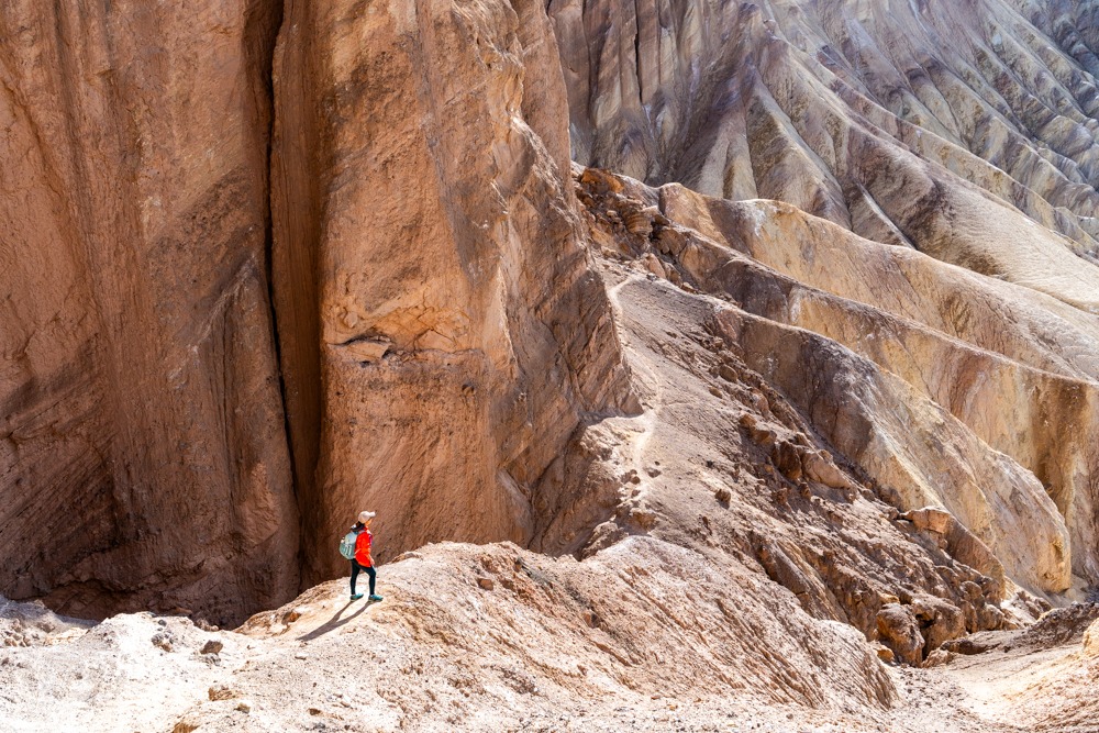 Hikers standing near the Red Cathedral viewpoint at the end of Golden Canyon with red cliffs towering above, realistic outdoor photography