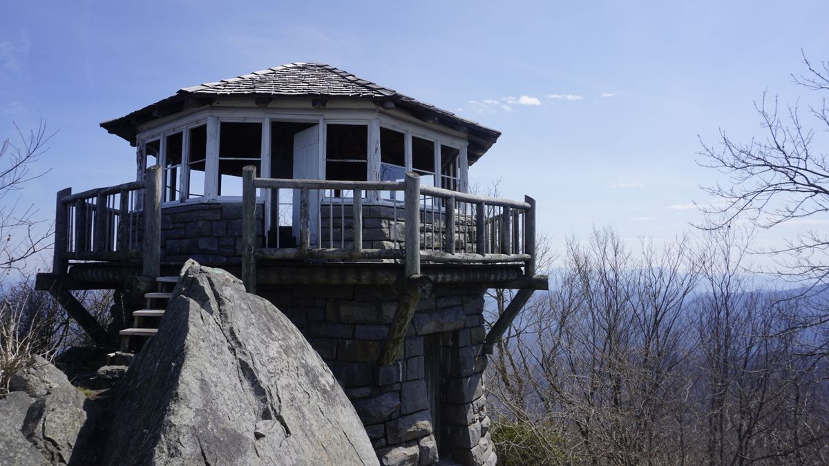 Historic fire tower perched on a rocky summit at Mount Cammerer with hazy mountain ridges in the distance, real outdoor photograph