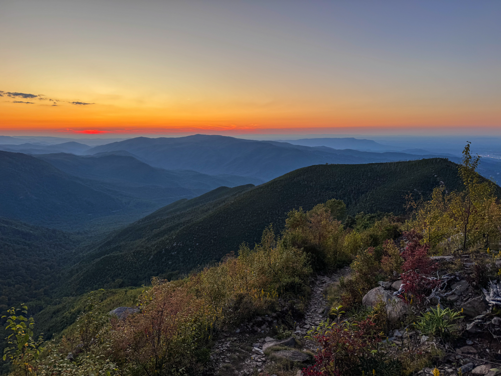 The Alum Cave Trailhead parking area in early morning light along Newfound Gap Road with cars and hikers preparing gear