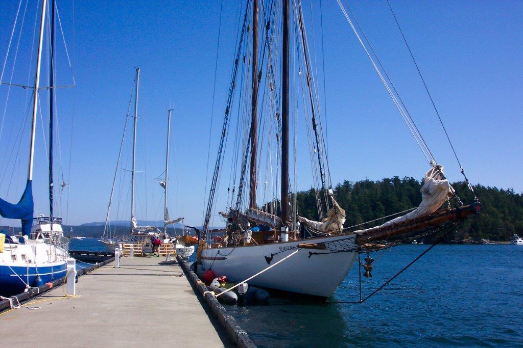 The Friday Harbor waterfront with wooden docks, small boats moored in the marina, and low clouds over the hills in the background, real travel photography