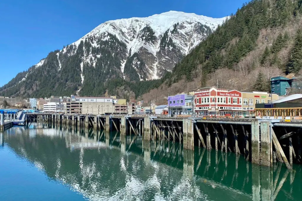 The Juneau, Alaska waterfront on a summer day with mountains behind town, low clouds, and a cruise ship near the docks