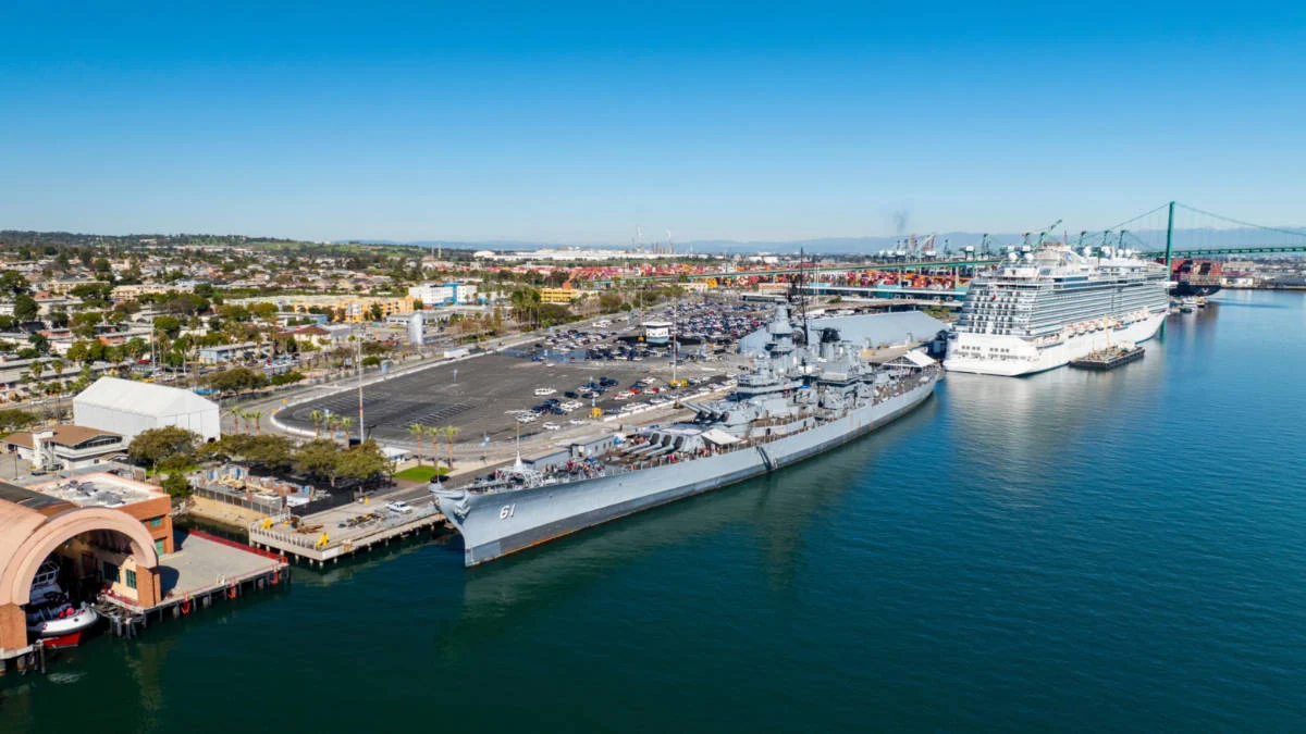 The Port of Los Angeles World Cruise Center terminal in San Pedro with parked cars and a cruise ship gangway visible in daylight
