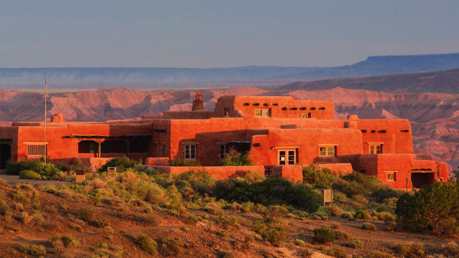 The historic Painted Desert Inn building in Petrified Forest National Park with desert scrub in the foreground and Painted Desert badlands stretching into the distance