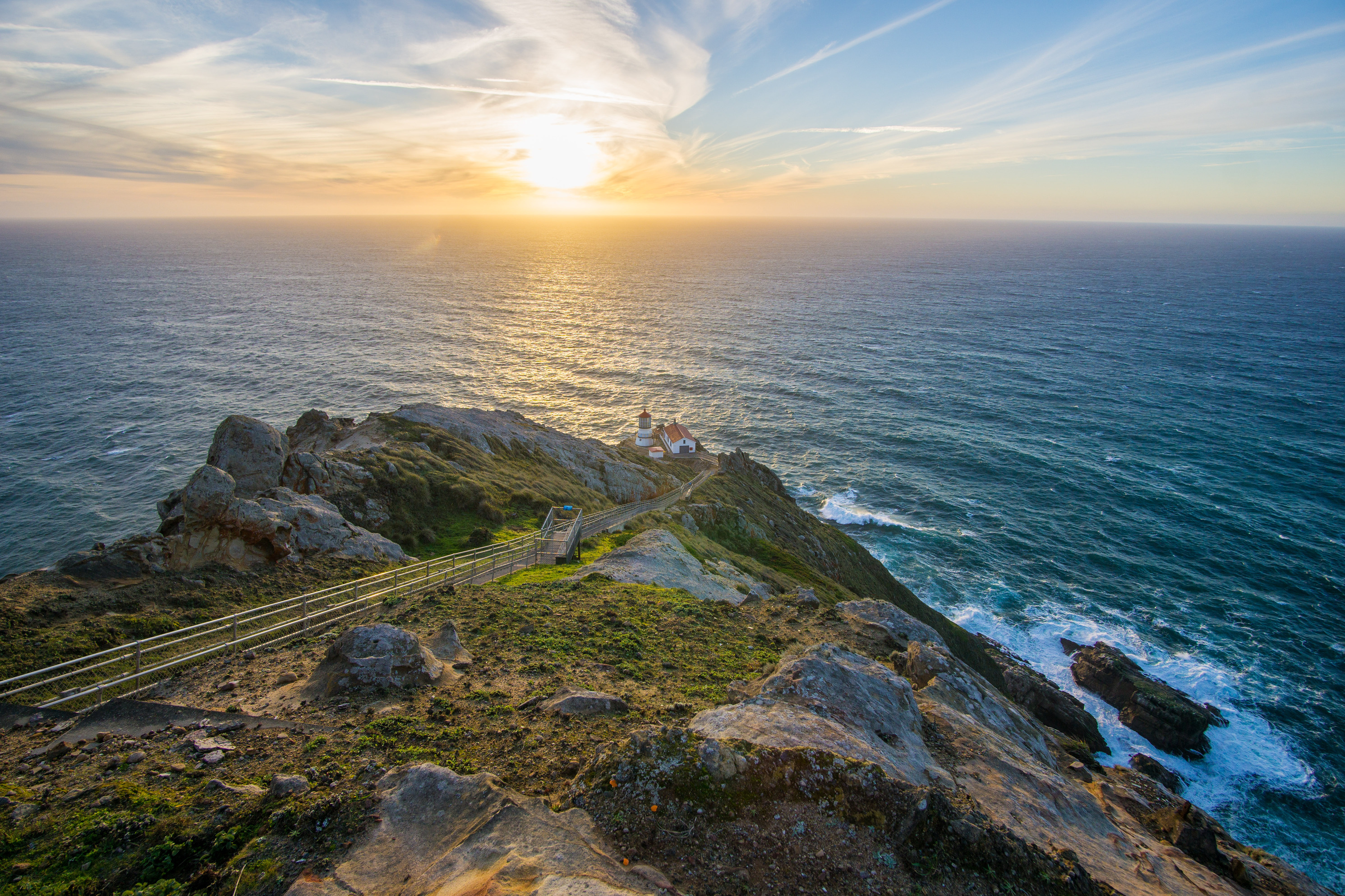 The steep stairway descending toward Point Reyes Lighthouse on a windy day with rugged coastal cliffs and choppy ocean below, realistic landscape photograph