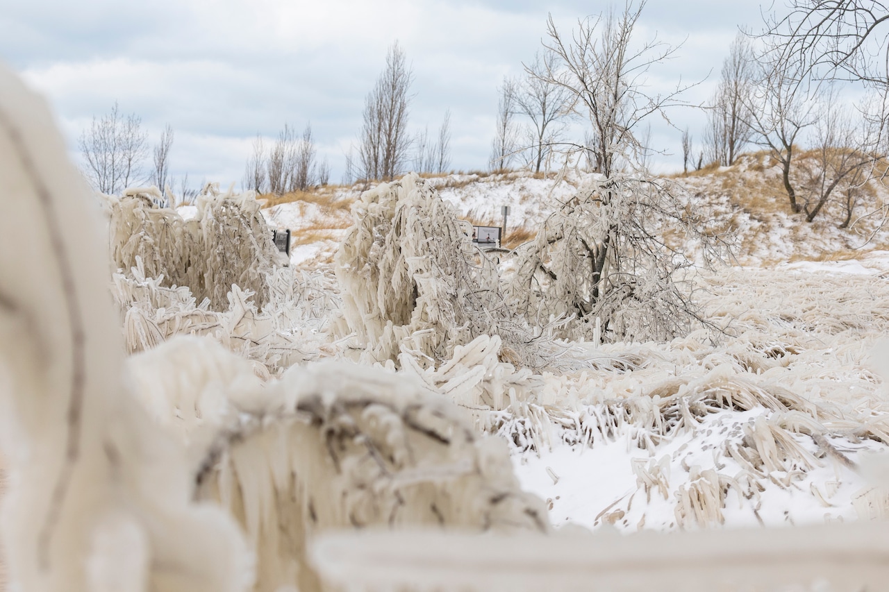 Visitors walking carefully on an icy wooden boardwalk in a national park during winter, snow piled along the sides, real photography style