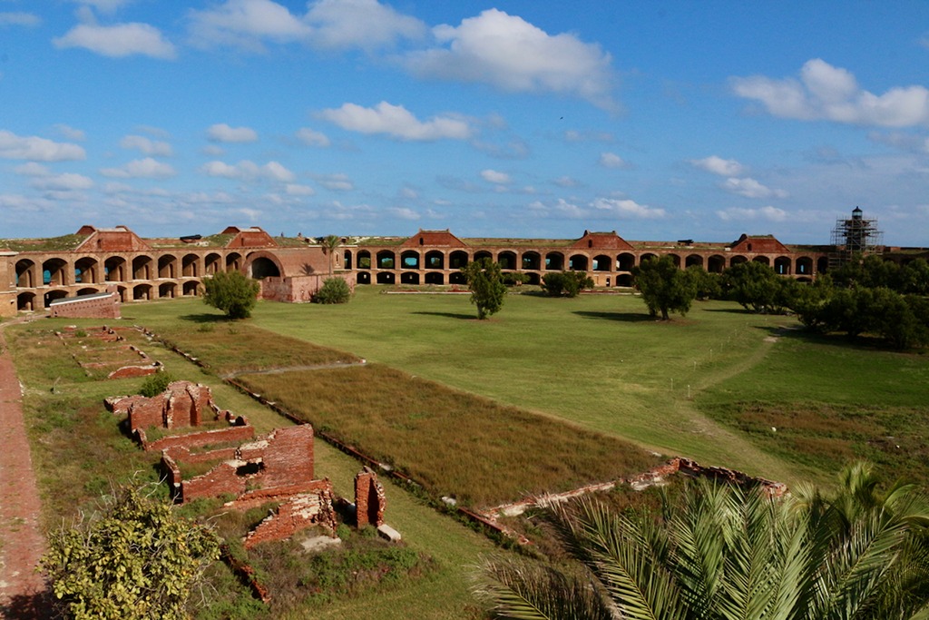Visitors walking in the sunny courtyard of Fort Jefferson with strong light and shadows on the brick walls